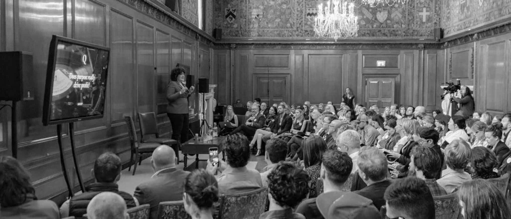 Audience attending a lecture on society's role in business education.