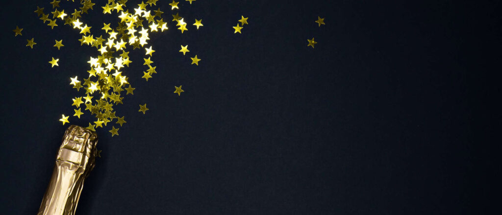 Stock image of champagne bottle and confetti against a black background
