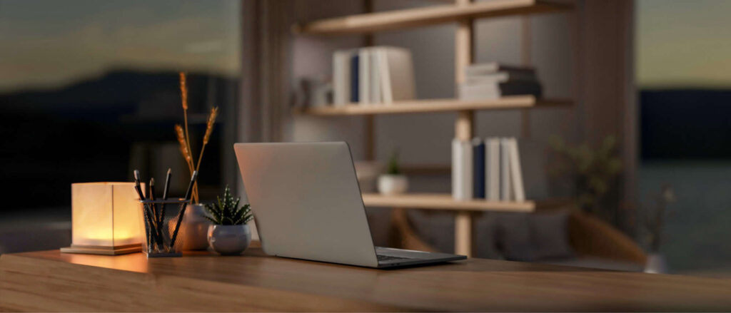 Stock image of a laptop on a desk with a golden lamp next to it